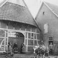 Alte Schmiede Historische Aufnahme einer alten Schmiede mit Fachwerk, Pferdekarren und Personen in traditioneller Kleidung.