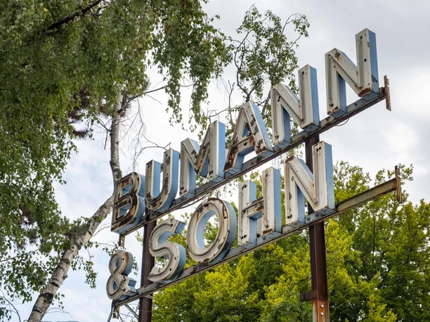 Bumann & Sohn A metal sign with the inscription "Bumann & Sohn" rises up against the cloudy sky.