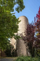 St. Alban Round tower made of red brick, surrounded by colorful autumn leaves and a bright sky.