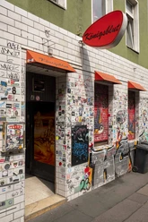 Königsblut Eine mit bunten Aufklebern bedeckte Wand am Eingang einer Bar namens "Königsblut" in Köln.