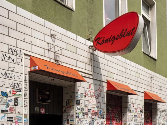 Königsblut Eine mit bunten Aufklebern bedeckte Wand am Eingang einer Bar namens "Königsblut" in Köln.A wall covered in colorful stickers at the entrance to a bar called "Königsblut" in Cologne.