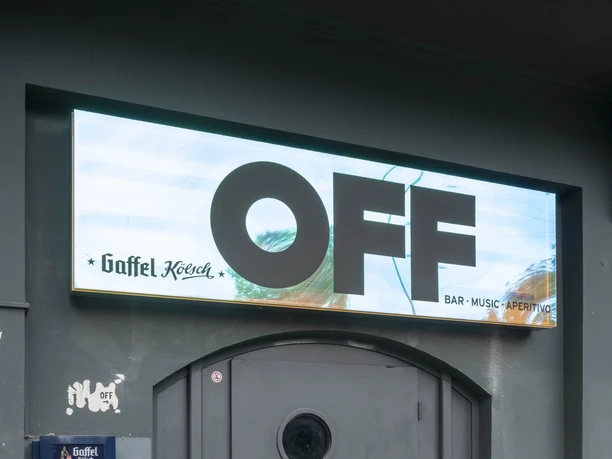 OFF Bar An einer dunklen Tür prangt ein schlichtes OFF-Schild. Graffiti schmücken die Wand.