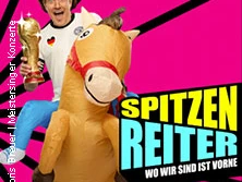 Ein Mann in einem Cowboykostüm reitet auf einem aufblasbaren Pferd vor einem pinkfarbenen Hintergrund.