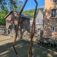 Das Kunstwerk Dowan von Robert Schad auf den Skulpturenwegen Langenberg Skulptur Dowan von Robert Schad aus Cortenstahl, eingebettet in eine städtische Landschaft mit Fachwerkhäusern.