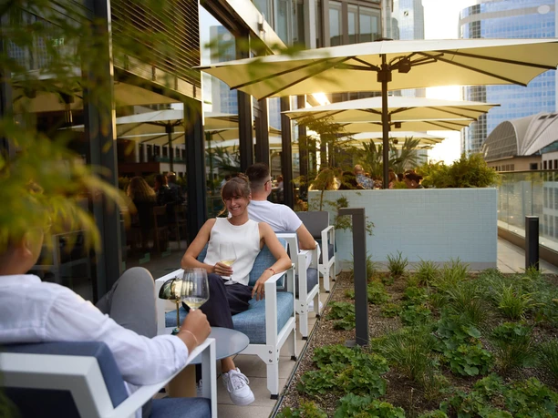 Person sitting on terrace enjoying a drink.