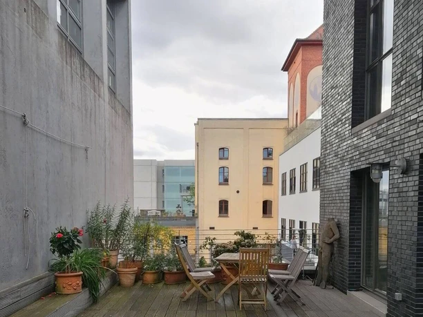 ROMANFABRIK Dachterrasse mit Pflanzentöpfen und Gartenmöbeln.
