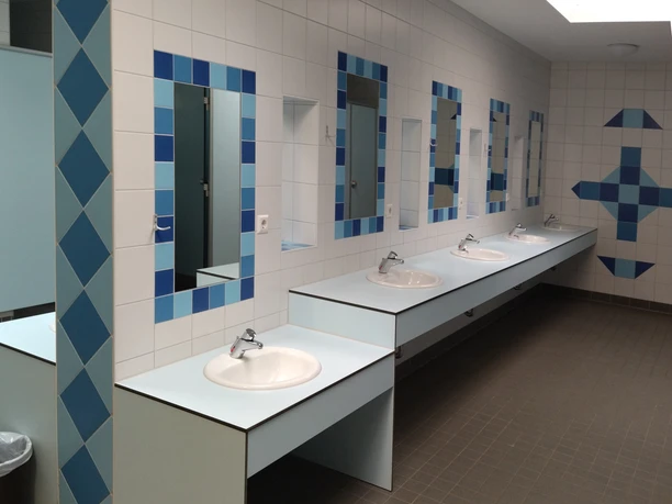 5_kcp_haren_sanitaer_MG_20230222_103138.jpg Moderne Sanitäranlage mit mehreren Waschbecken, Spiegeln und hellblauen Fliesen im KNAUS Campingpark.