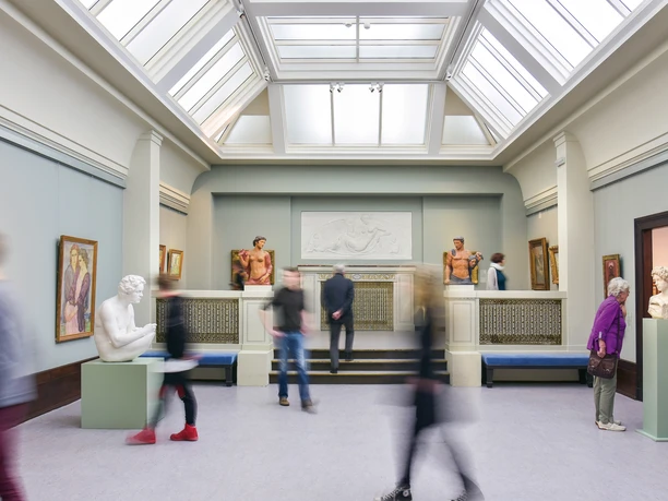 HHI_7897.jpg Innenraum eines Museums mit Skulpturen und Gemälden, Besucher bewegen sich durch den Raum.