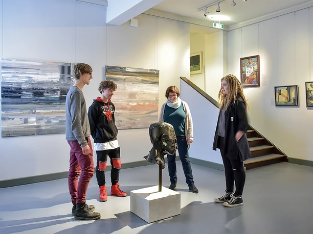 HHI_7973.jpg Vier Personen betrachten eine Skulptur in einer modernen Galerieumgebung.