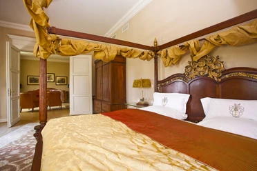 Himmelbett in einem eleganten Schlafzimmer mit Holzmöbeln und sanfter Beleuchtung.