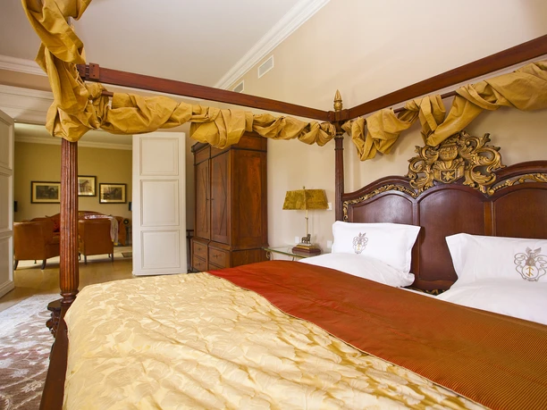 Hamm2014_Gut_Kump_Hotel1-CCBYSA_ThorstenHübner.jpg Himmelbett in einem eleganten Schlafzimmer mit Holzmöbeln und sanfter Beleuchtung.