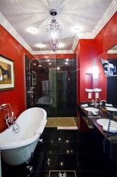 Luxuriöses Badezimmer mit freistehender Badewanne und roter Wandverkleidung.