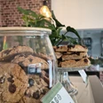 zuckerschmiede.jpg Ein Café mit rustikaler Backsteinwand, Cookies im Glas und Schokotörtchen auf einem Teller.