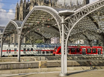 Köln Hauptbahnhof Köln Hauptbahnhof mit modernem Bahnsteig und weiß-rotem Zug, im Hintergrund der imposante Kölner Dom.Cologne Central Station with modern platform and white and red train, with the imposing Cologne Cathedral in the background.