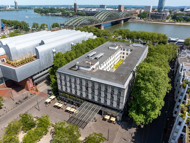 DJI_20240730140054_0042_D.jpg Luftaufnahme der Kölner Innenstadt mit Hohenzollernbrücke, Rhein und modernem Hotelgebäude.