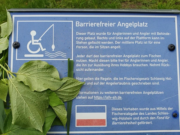 Informationsschild_Barrierefreier Angelplatz Barrierefreies Schild an einem Angelplatz. Text informiert über Zugangsmöglichkeiten und Nutzung.