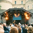 gamescom city festival Ein Gitarrenspieler performt auf einer outdoor-Bühne, umgeben von einem Publikum vor einer historischen Festung.A guitar player performs on an outdoor stage, surrounded by an audience in front of a historic fortress.
