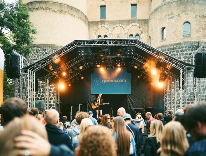gamescom city festival Ein Gitarrenspieler performt auf einer outdoor-Bühne, umgeben von einem Publikum vor einer historischen Festung.A guitar player performs on an outdoor stage, surrounded by an audience in front of a historic fortress.