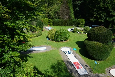 Minigolf Binder_01_Stadt Velbert_Lisa Krick.JPG Eine Minigolfanlage eingebettet in grüne Hecken und Rasenflächen, mit mehreren Bahnen und schattigen Ecken.