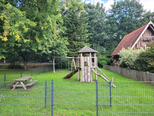 Spielplatz Luershoff Spielplatz Luershoff mit Kletterturm, Rutsche, Schaukeln und Picknicktisch auf grünem Rasen neben einem Fachwerkhaus