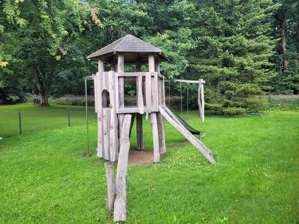 Spielplatz_Luershoff__01.jpg olzspielplatz mit Kletterturm, Rutsche und Schaukel auf dem Spielplatz Luershoff, umgeben von grünen Bäumen