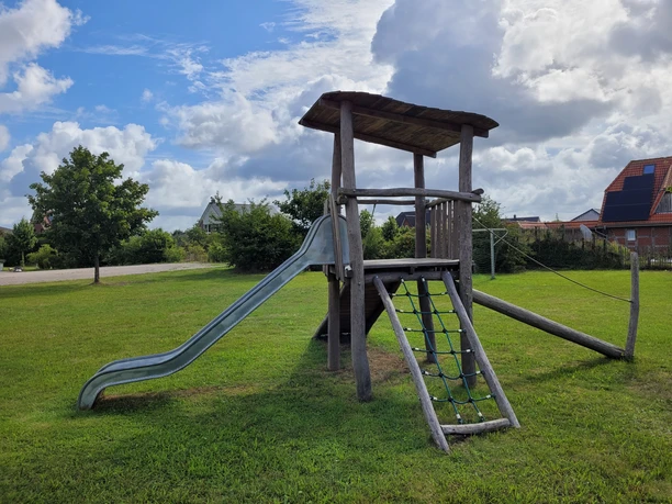 Spielplatz_in_Bispingen_am_Droegenberg_.jpg Spielplatz in Bispingen am Drögenberg mit hölzernem Klettergerüst, Rutsche und Kletternetz auf einer Wiese