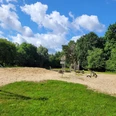 Badeteich_Steinbeck_.jpg Spielplatz mit Sandfläche, Klettergerüst und Schaukeln am Badeteich Steinbeck, umgeben von Bäumen unter blauem Himmel mit Wolken