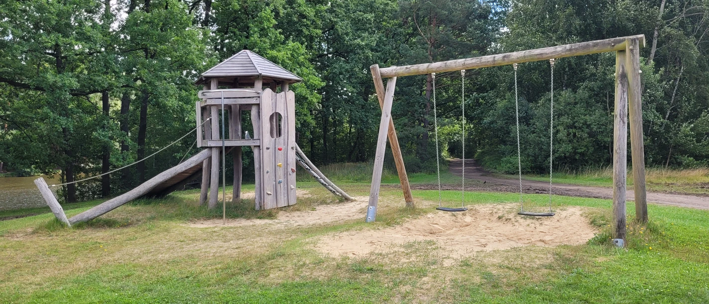 Spielplatz_am_Brunausee_.jpg pielplatz am Brunausee mit Holzturm, Kletterwand, Seilrutsche und Doppelschaukel auf Grasfläche