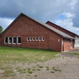 Mehrzweckhalle_Steinbeck_2025.jpg Mehrzweckhalle Steinbeck, ein langgestrecktes Backsteingebäude mit mehreren Fenstern und einem Satteldach unter bewölktem Himmel
