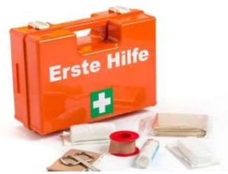 Ein orangefarbener Erste-Hilfe-Kasten mit weißem Text sowie Verbandmaterialien und Schere im Vordergrund.