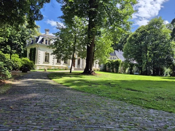 Palaisgarten.jpg Ein weitläufiger Garten mit gepflegtem Rasen und einem stattlichen, von Bäumen umringten Gebäude.