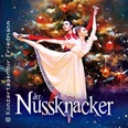 Ein Tänzerpaar in klassischen Posen vor einem festlich geschmückten Weihnachtsbaum beim Nussknacker-Ballett.
