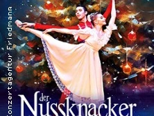 Ein Tänzerpaar in klassischen Posen vor einem festlich geschmückten Weihnachtsbaum beim Nussknacker-Ballett.
