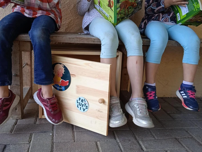 Kinder schauen sich Bücher aus der Bücherkiste an.