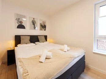 Schlafbereich Helles Schlafzimmer mit zwei Einzelbetten, weicher Beleuchtung und moderner Kunst an der Wand.