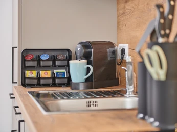 ,,Ein guter Start in den Tag ..." :) Kompakte Küchenzeile mit Nespresso-Maschine, vier Teebeuteln, Messerblock und blauer Tasse.
