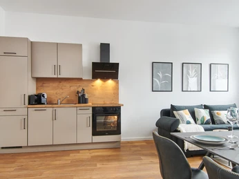 Wohnraum Moderne offene Küche und Wohnzimmer mit grauem Sofa, Holzboden, elegant gedecktem Esstisch.