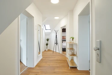 Eingangsbereich mit Flur Heller Flur mit Holzboden und moderner Dekoration, Türen führen zu weiteren Räumen, Garderobe zentral.