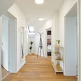 Eingangsbereich mit Flur Heller Flur mit Holzboden und moderner Dekoration, Türen führen zu weiteren Räumen, Garderobe zentral.