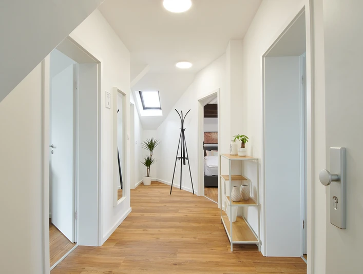 Eingangsbereich mit Flur Heller Flur mit Holzboden und moderner Dekoration, Türen führen zu weiteren Räumen, Garderobe zentral.