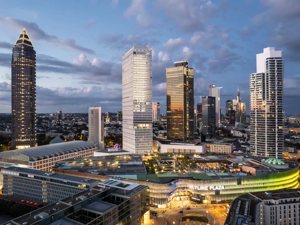 Skyline Garden - Drohnenaufnahme Skyline Plaza bei Dämmerung, umgeben von beleuchteten Hochhäusern.