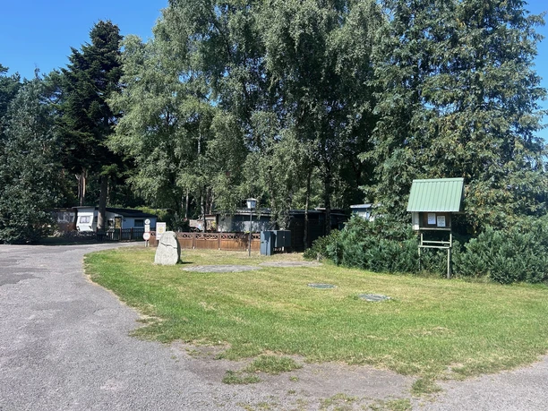Campingplatz Zum Naturpark | 2 Zufahrt zum Campingplatz mit schattigen Bäumen, Wiesenfläche und Stellplätzen mit Wohnwagen.