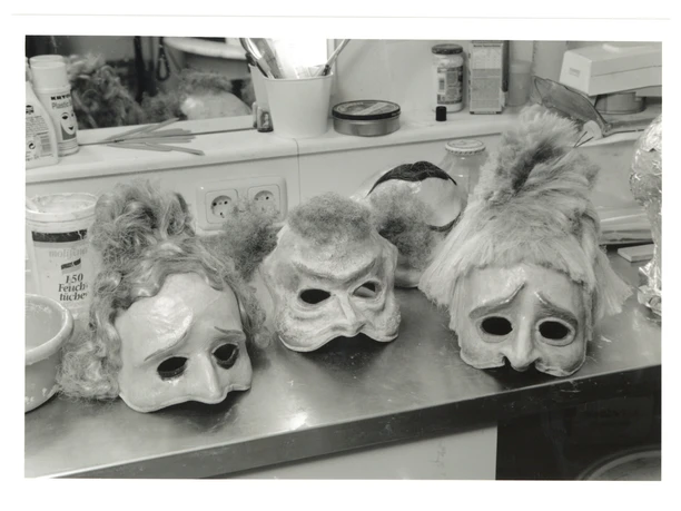 200 Jahre Theater Aachen_Masken zu der Oper - Neues vom Tage (c) Stadt Aachen.jpg Schwarz-weiß Foto von verschiedenen Theatermasken auf einem Tisch mit einem Spiegel dahinter.