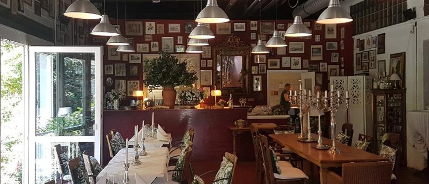 Loft Age Gemütliches Restaurant mit vielen Bildern an der Wand, langen Tischen und Kronleuchtern.