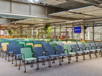 Mittelamerika Reihen bestuhlter bunter Stühle in einem modernen, hellen Raum mit industriellen Designelementen.Rows of colorful chairs in a modern, bright room with industrial design elements.