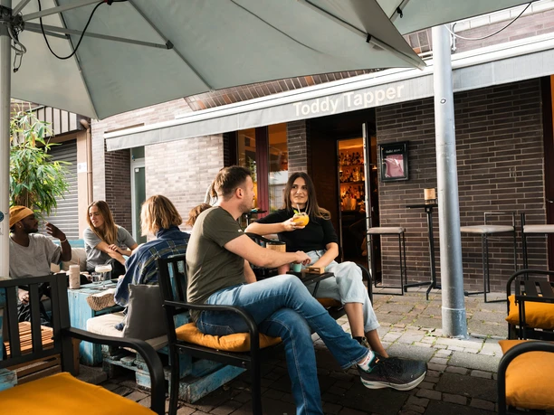 Toddy Tapper The Toddy Tapper in Cologne with a relaxed atmosphere, people enjoying drinks in the outdoor area.
