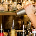 Bar Ein Barkeeper schüttelt einen Edelstahl-Shaker, im Hintergrund sind Flaschen zu sehen.A bartender shakes a stainless steel shaker, bottles can be seen in the background.