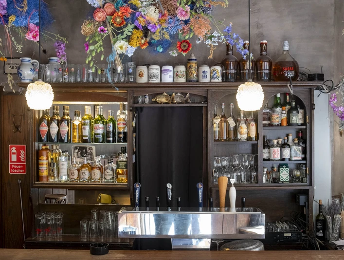 Forelle Blau Barbereich mit farbenfrohem Blumenschmuck und diversen Getränken; warmes und einladendes Ambiente.Bar area with colorful floral decorations and various drinks; warm and inviting ambience.
