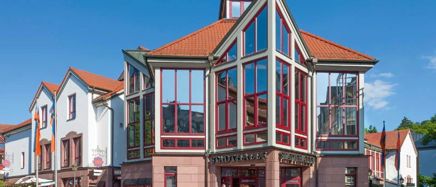 Stadthalle Idstein Die Stadthalle Idstein mit rotem Dach und großen Fenstern unter blauem Himmel.