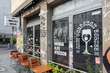 Zum Goldenen Schuss Kneipe mit Graffiti-verzierten Fenstern, die moderne urbane Kultur widerspiegeln.